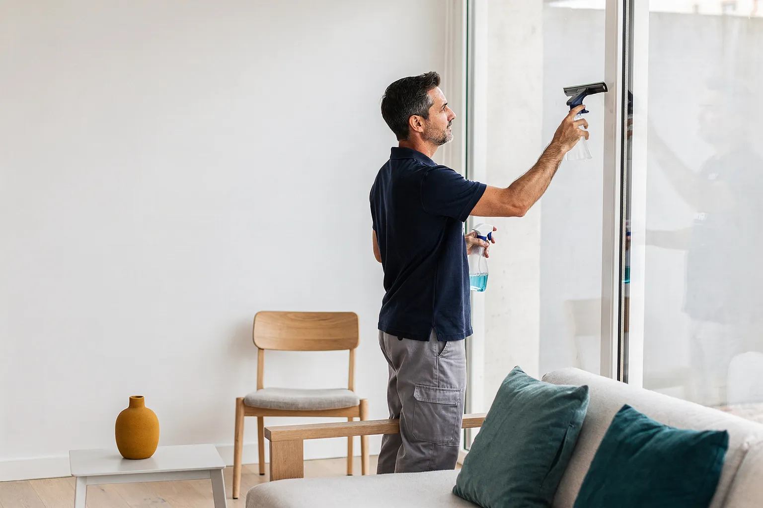 Profesional de limpieza limpiando los ventanales de un salón luminoso